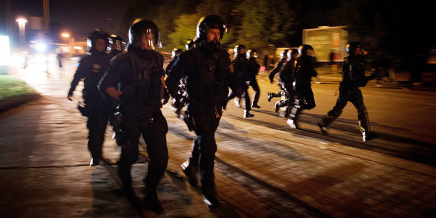 Polizisten in Schutzkleidung auf einer nächtlich beleuchteten Straße