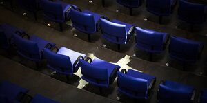 Eine leere Stuhlreihe im Bundestag wird von Sonnenlicht beschienen