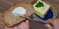 Ein Mädchen streicht Butter auf eine Scheibe Brot.