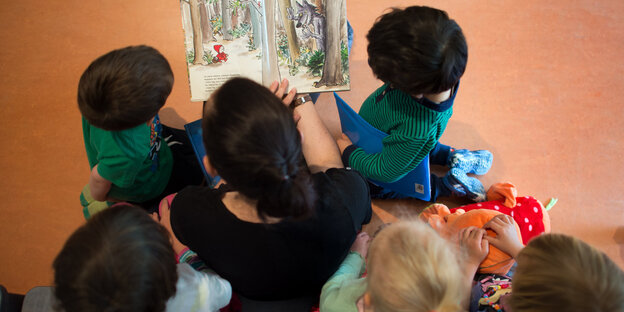 Eine Erzieherin liest Kindern aus einem Buch vor Eine Erzieherin liest Kindern aus einem Buch vor