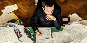 Der Komponist Jörd Widmann an einem Tisch voller Manuskripte