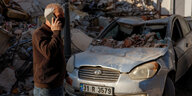 Eine Person telefoniert vor einem zerstörten Haus