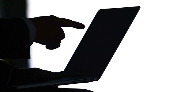 Zeigefinger zeigt auf aufgeklappten Laptop Zeigefinger zeigt auf aufgeklappten Laptop