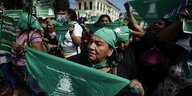 Frauen demonstrieren mit grünen Tüchern worauf Slogangs für illegale Abtreibung stehen