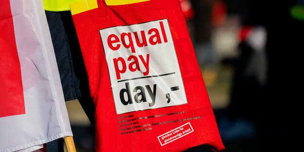 "equal pay day ,-" steht auf einer Tasche einer Teilnehmerin an einem Warnstreik.