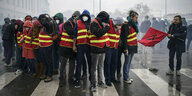 Gewerkschaftsmitglieder in roten Warnwesten stehen auf einer Straße