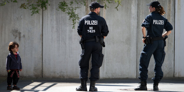 Ein Kind steht neben zwei Polizisten Ein Kind steht neben zwei Polizisten