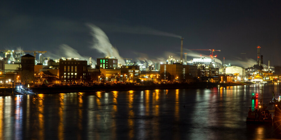 Der Rhein fließt bei Nacht im Vordergrund, im Hintergrund die hellbeleuchteten Chemie-Anlagen von BASF