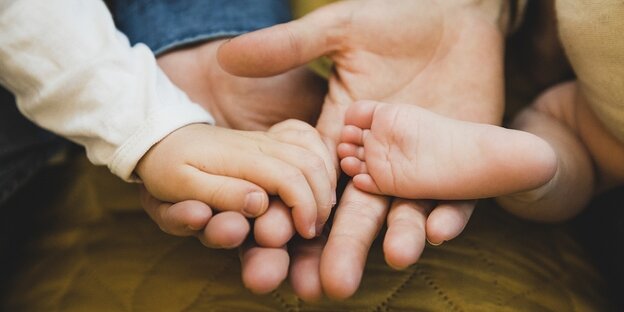 Child's hand, child's foot and the hands of two adults