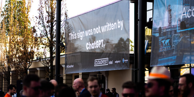 Menschen stehen vor einem Schild, auf dem steht "This sign was not written by ChatGPT"