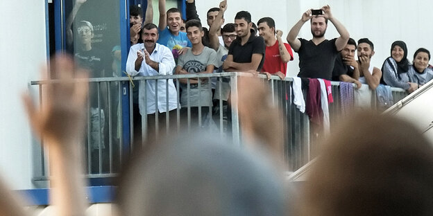 Demonstranten vor der Flüchtlingsunterkunft in Heidenau. Vom Balkon winken einige Flüchtlinge zurück. Demonstranten vor der Flüchtlingsunterkunft in Heidenau. Vom Balkon winken einige Flüchtlinge zurück.