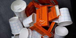 Leere Medikamentenpackungen und Pappbecher liegen in einem Mülleimer