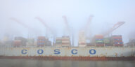 Das Bild zeigt ein Containerschiff von Cosco, das im dichten Nebel am Containerterminal Tollerort liegt.