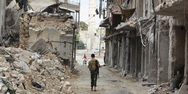 Bewaffneter geht durch eine zerstörte Gasse in Aleppo. Bewaffneter geht durch eine zerstörte Gasse in Aleppo.