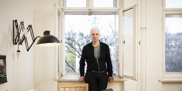 Paul Brodowsky is standing at the open window of an apartment in an old building