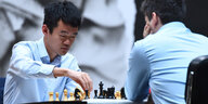 Zwei Männer im hellblauen Hemd sitzen gegenüber und spielen Schach