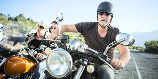 Drei Motorradfahrer von vorne auf einer Landstraße im Sommer Drei Motorradfahrer von vorne auf einer Landstraße im Sommer