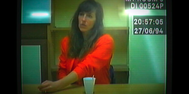 Video-Still einer Frau, die an einem Tisch sitzt Video-Still einer Frau, die an einem Tisch sitzt