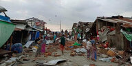 Eine Straße voller Trürmmer von stark beschädigten Häusern und Hütten in Sittwe