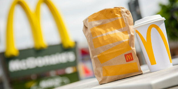 McDonald's to-go bags and a matching to-go cup are in front of a Tübingen McDonald's branch.