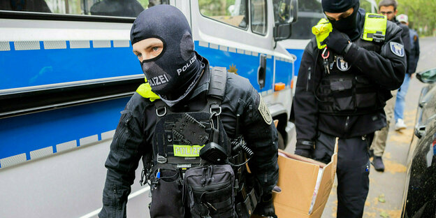 Two police officers carry a box with confiscated items