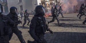 Uniformite Polizisten mit Schutzhelmen rennen durch eine Straße