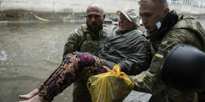 Ukrainische Rettungskräfte tragen eine Zivilistin am 11. Juni 2023