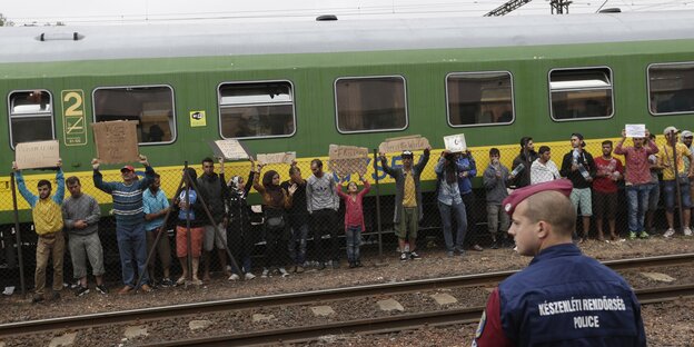 Menschen stehen mit Transparenten an einem Zug Menschen stehen mit Transparenten an einem Zug
