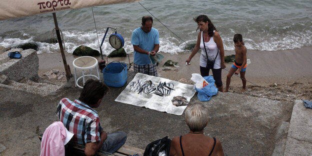 Ein Mann verkauft frischen Fisch an einem Strand bei Athen Ein Mann verkauft frischen Fisch an einem Strand bei Athen