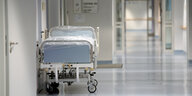 In einem langen Krankenhausflur ist in der Ferne ein Krankenbett an die Wan gestellt. Alles ist Menschenleer.