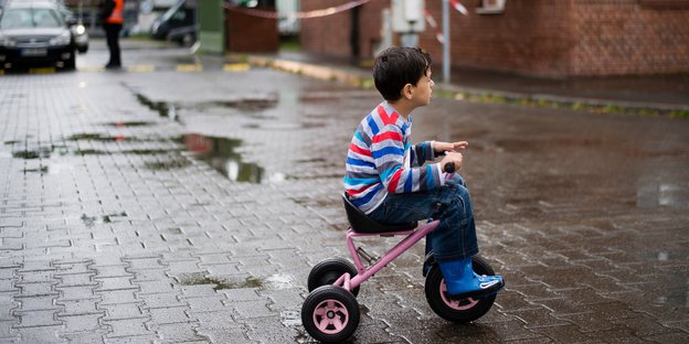 Junger Flüchtling auf Dreirad.