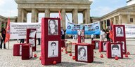 Porträts von Menschen auf roten Kisten vor dem Brandenburger Tor
