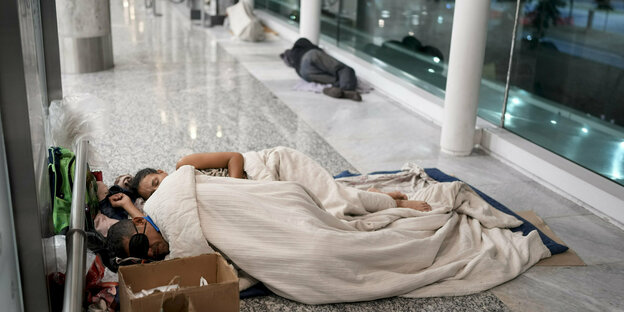 Obdachlose nächtigen im April im Flughafenterminal von Buenos Aires auf dem Boden: Im Vordergrund zwei Personen uner Decken,