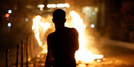 Die Silhuette einer Person vor den Flammen einer brennenden Barrikade