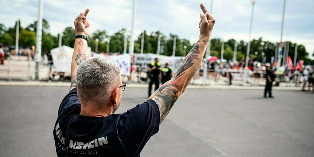 A man in a Rammstein shirt shows both middle fingers to a demonstration with critics of the band
