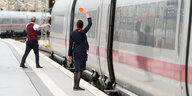 Zugbegleiter der DB Deutsche n Bahn AG signalisieren dem aus dem Fenster schauenden Lokführer mit einer roten Kelle die Abfahrt eines ICE im Hauptbahnhof Leipzig