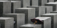 Spaziergänger mit Schirm in Berlin im Holocaust-Mahnmal