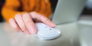 Eine Frauenhand hält eine Computre Maus