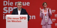 Die neue SPD-NRW-Doppelspitze Achim Post und Sarah Philipp stehen auf einer Bühne am Podium, beide seriös gekleidet