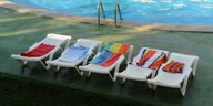 Leere, mit Handtüchern reservierte Sonnenliegen an einem Hotel-Pool