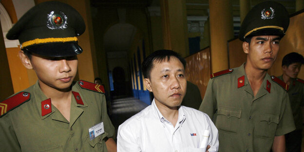 Der Dissident Nguyen Bac Truyen (Mitte) wird in Handschellen vor das Volksgericht von Ho-Chi-Minh-Stadt geführt
