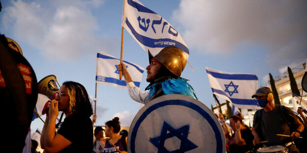Demonstrierende mit Israelflaggen, einer trägt einen goldenen Helm