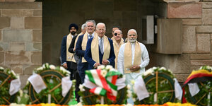 Die Staats- und Regierungschefs der G20 stehen aufgereiht vor Blumenkränzen mit verschiedenen Länderflaggen. Ganz vorne sind der amerikanische Präsident Joe Biden und der indische Premierminister Narendra Modi zu sehen. In der zweiten Reihe Bundeskanzler Olaf Scholz mit Augenklappe.