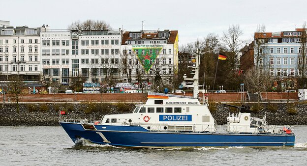 Ein Polizeischiff fährt vor der Hafenstraße über die Elbe.