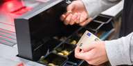 Offene Kasse im Supermarkt mit Händen, die Geld rein- oder raussortieren