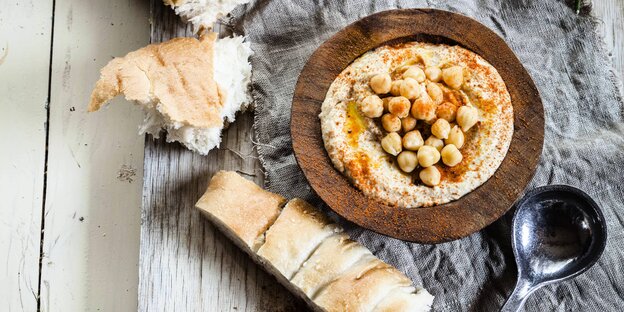Eine Schüssel mit Hummus steht auf einem Tisch. Eine Schüssel mit Hummus steht auf einem Tisch.
