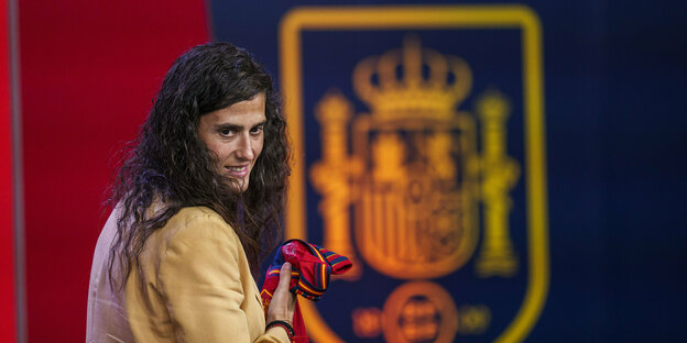 Spain's new national coach Montse Tomé with a mischievous grin in front of the coat of arms of the Spanish Football Association