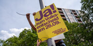 EIn Plakat "Ja zum Volksentscheid" wird an einer Laterne angebracht