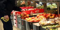 Ein Mann kauft in einem Berliner Supermarkt Obst ein, er nimmt sich ein Netz mit Äpfeln