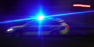 Ein Polizeiwagen fährt mit Blaulicht durch die Nacht